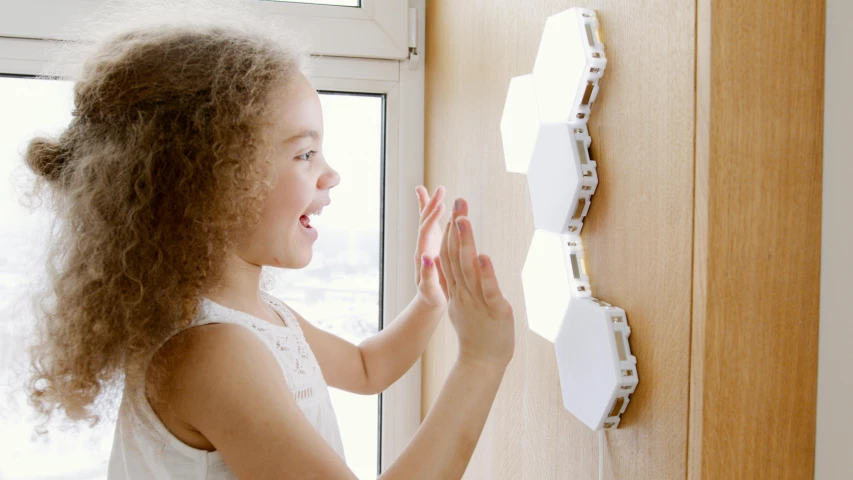 a little girl that is standing in front of a door, interactive art, hexglow, white panels, at home, holding up a night lamp