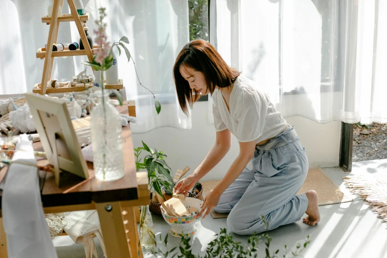 a woman sitting on the floor in front of a painting easel, by Tan Ting-pho, pexels contest winner, its bowl overflowing with plants, hong june hyung, profile image, having a snack