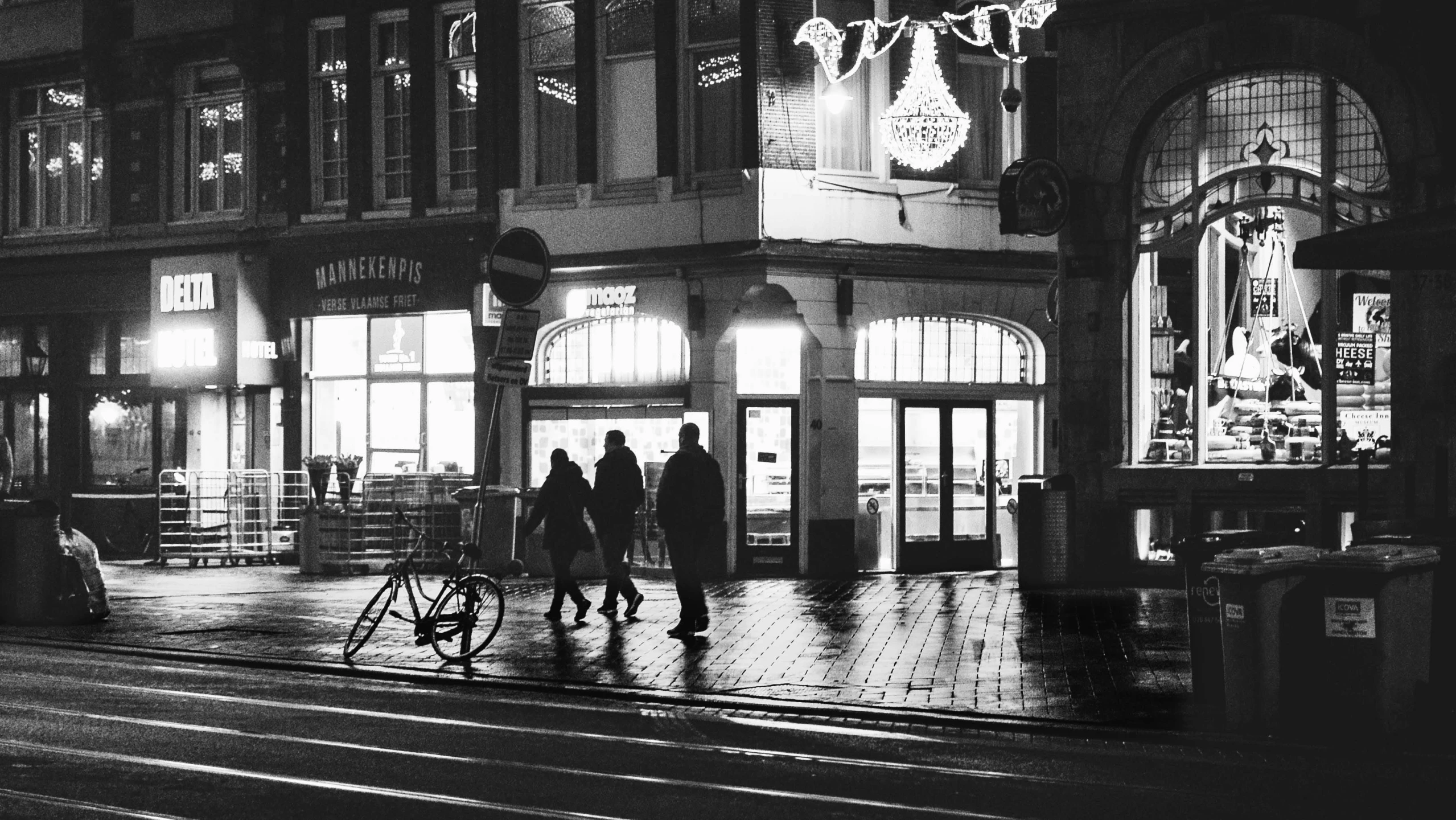 a couple of people walking down a street at night, a black and white photo, by Jan Tengnagel, pexels contest winner, warm street lights store front, wintertime, city morning, people shopping