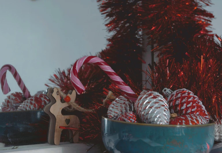 a blue bowl filled with candy canes next to a christmas tree, a picture, by Georgina Hunt, pexels, red brown and grey color scheme, metallic red, thumbnail, cinematic detail