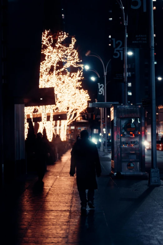 a person walking down a city street at night, christmas lights, new york in the seventies, fire lit, promo image