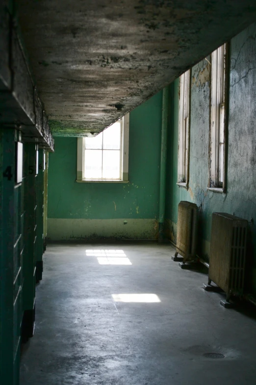 an empty room with two windows and a radiator, flickr, sickly green colors, natural prison light, teal aesthetic, tattered green dress