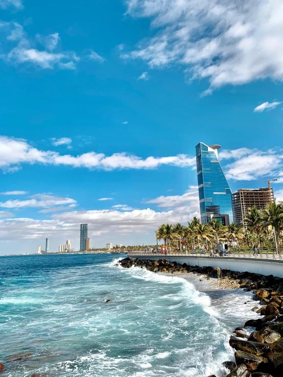 a large body of water next to a beach, a picture, pexels contest winner, hurufiyya, karachi skyline background, in spain, 💋 💄 👠 👗, slide show