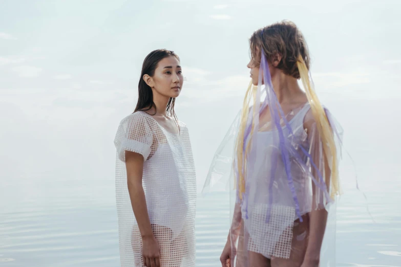 two women standing next to each other on a beach, inspired by Kim Tschang Yeul, unsplash, gutai group, futuristic fashion show, translucent skin, quiet beauty, on a lake