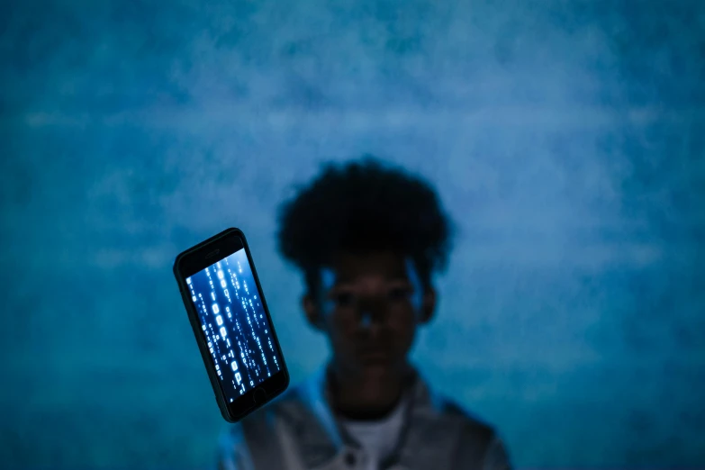 a close up of a person holding a cell phone, a hologram, by James Morris, pexels contest winner, conceptual art, ashteroth, ryoji, a person standing in front of a, blue backlight