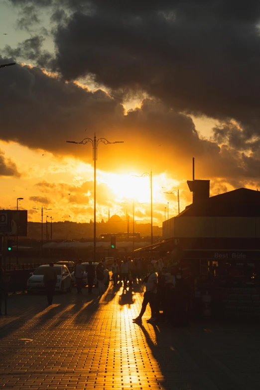 a group of people walking down a street at sunset, by Nadir Afonso, sun after a storm, market, rays, yellow sky