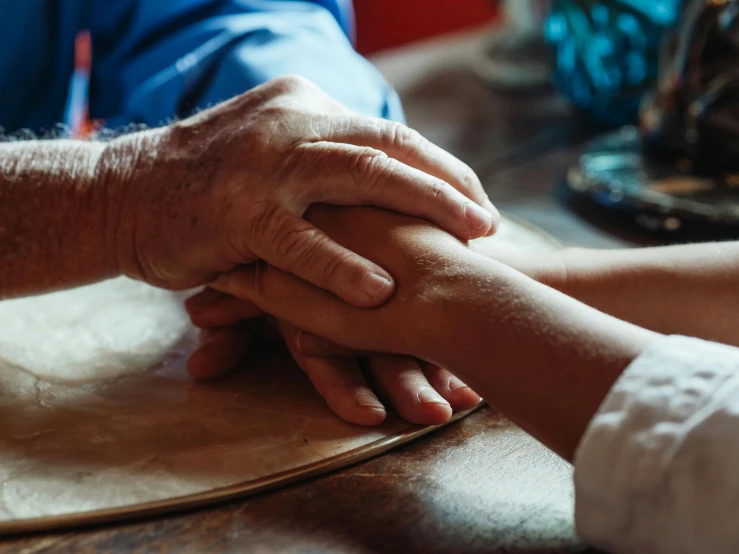 a close up of a person holding a person's hand, on a table, grandfatherly, uploaded, brown