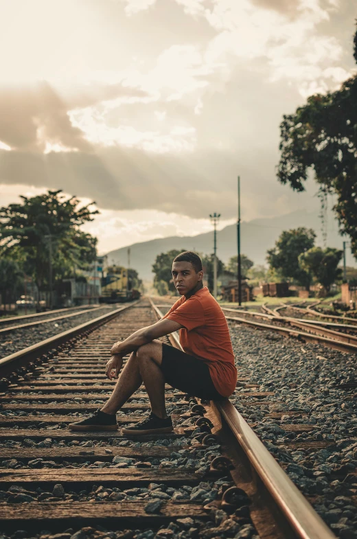 a man sitting on a rail road track, a picture, pexels contest winner, ariel perez, around 1 9 years old, color graded, in the yard