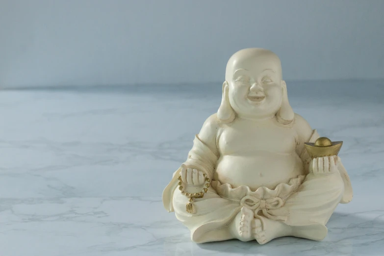 a white buddha statue sitting on top of a table, a statue, inspired by Tani Bunchō, luscious with sesame seeds, sitting on the floor, holding a bell, bowater charlie