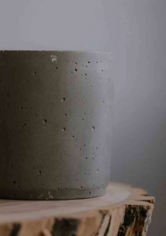 a gray cup sitting on top of a wooden table, inspired by Hendrik Gerritsz Pot, concrete art, frontal close up, medium height, bottom lighting, product shot