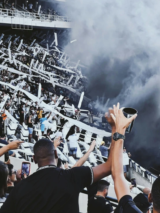 a group of people standing next to each other in a stadium, by Lucia Peka, pexels contest winner, happening, black smoke, an all white human, instagram post, cheering