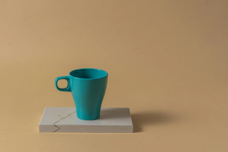 a blue cup sitting on top of a piece of paper, inspired by Raoul De Keyser, unsplash, photorealism, square, product display photograph, turquoise, cast