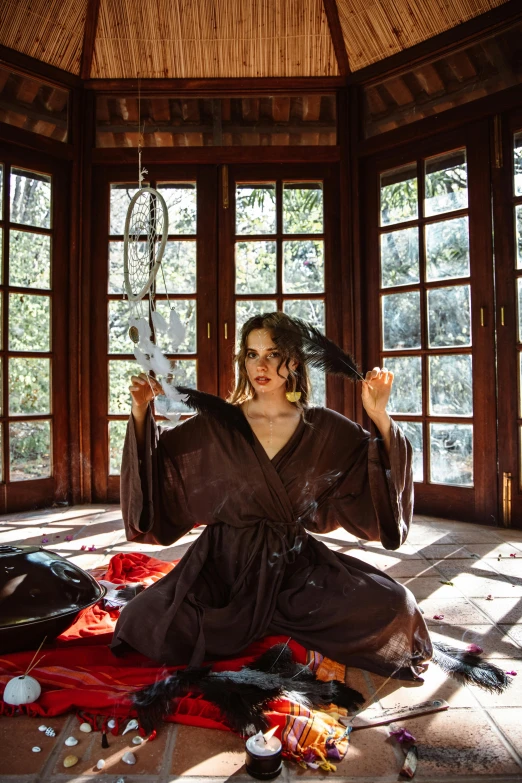 a woman sitting on the floor in a room, an album cover, inspired by Artemisia Gentileschi, magical realism, occult robes, maya ali as a d&d sorcerer, taken in the early 2020s, an ancient