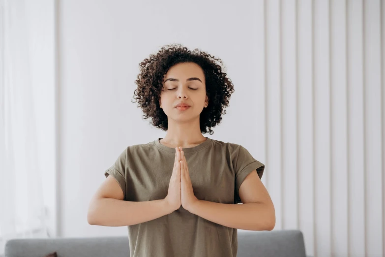 a woman doing yoga in a living room, trending on pexels, hurufiyya, small round face, background image, indian girl with brown skin, hands crossed