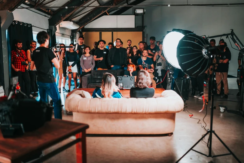 a group of people standing around a couch in a room, pexels contest winner, film studio, movie setup, photoshoot for skincare brand, cinestill 400t