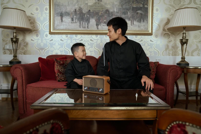 a couple of men standing next to each other in a living room, an album cover, inspired by Zhang Shengwen, pexels contest winner, little kid, ao dai, radio, medium shot portrait