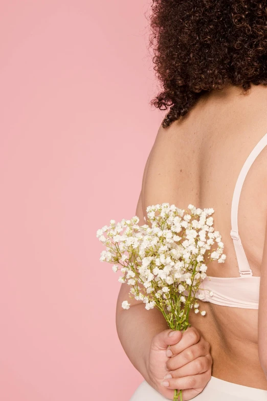 a woman in a white underwear holding a bouquet of flowers, inspired by Elsa Bleda, happening, bra strap, back to camera, wearing bra, growing