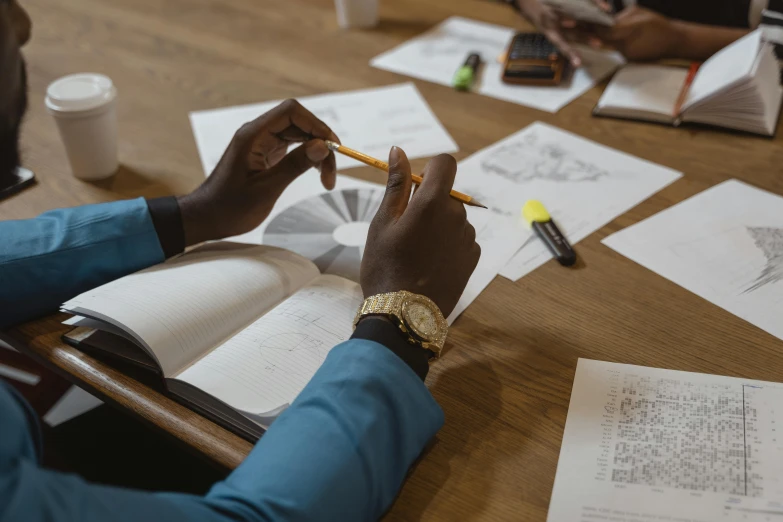 a group of people sitting around a wooden table, a drawing, pexels contest winner, drawing sketches on his notebook, riyahd cassiem, working in an office, clear focused details