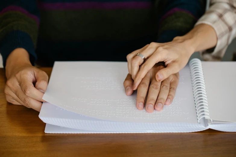 a close up of a person's hands on a notebook, private press, holding each other hands, background image, intricate writing, hand on table