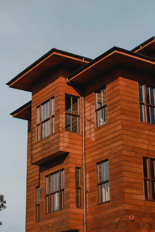 a tall wooden building with lots of windows, unsplash, arts and crafts movement, high-quality photo, wooden house, brown, modern