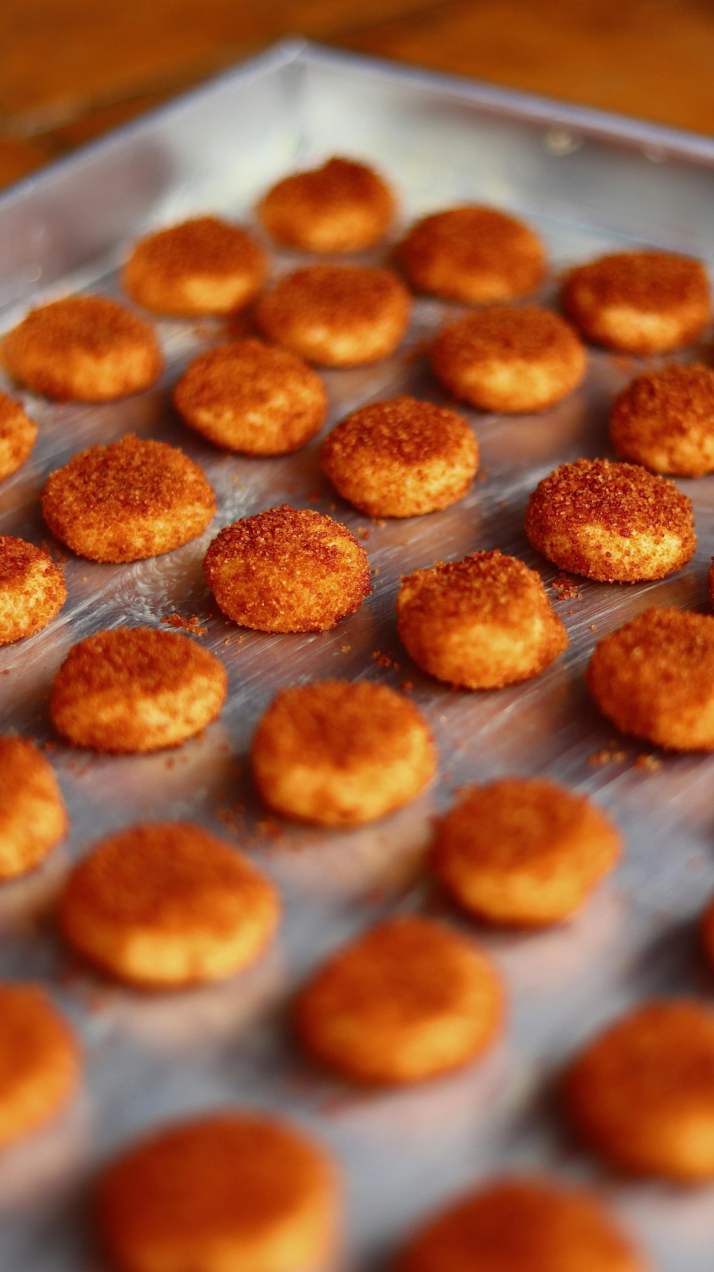 a pan filled with cookies sitting on top of a wooden table, by Matt Cavotta, pexels, pop art, chicken nuggets, paprika, circles, close up. macro. hyper realistic