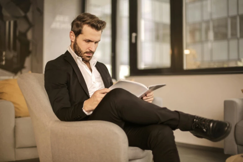 a man sitting in a chair reading a book, pexels contest winner, wearing causal black suits, profile image, attractive photo, maintenance photo