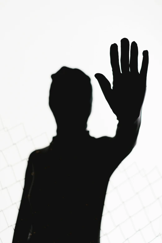 a silhouette of a person holding their hand up, face partially obscured, translucent body, scaled arm, back and white