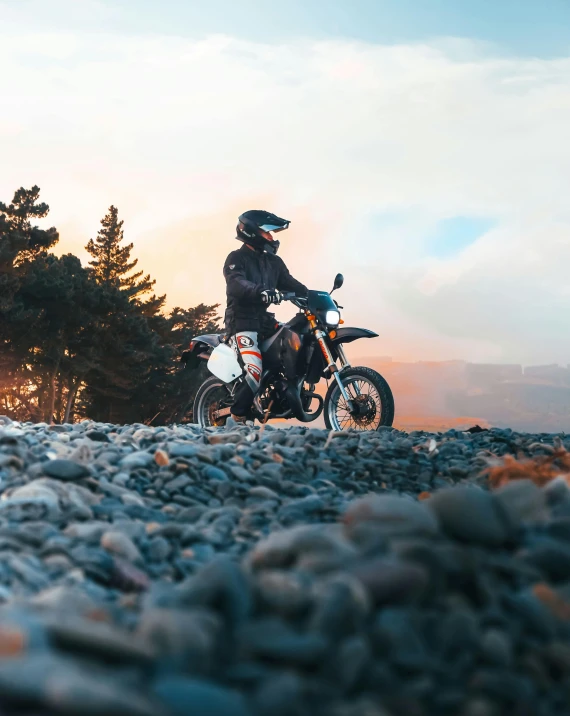 a person riding a motorcycle on a rocky road, during a sunset, profile image