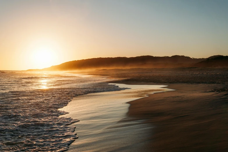 a person riding a surfboard on top of a sandy beach, pexels contest winner, australian tonalism, sun rise, beach is between the two valleys, soft-sanded coastlines, hollister ranch