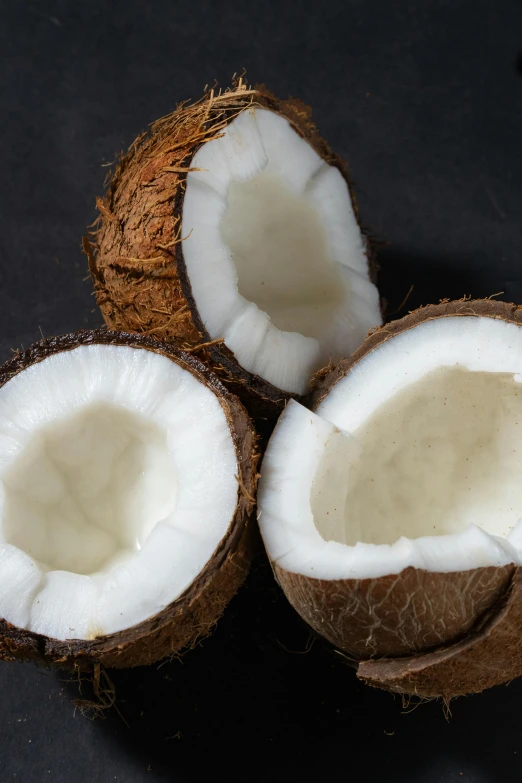 a couple of coconuts sitting on top of a table, in front of a black background, up-close, multiple stories, high quality product image”