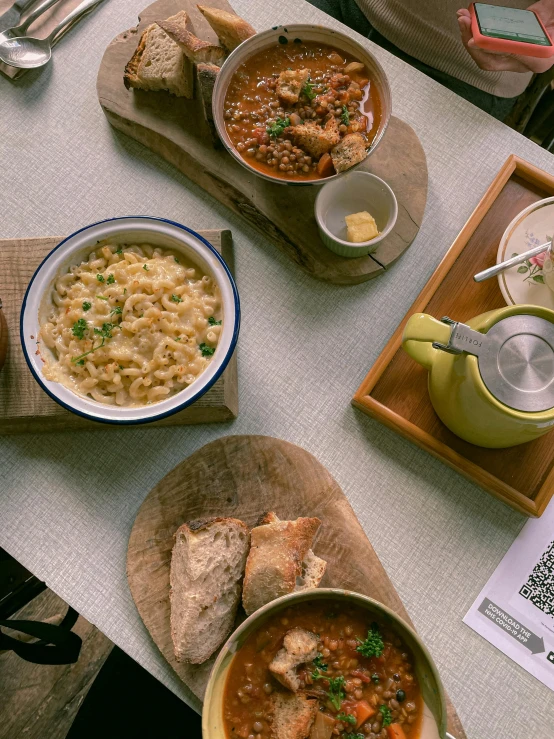 a table topped with bowls and plates of food, lots of macaroni! over a desk, cozy cafe background, flatlay, good soup