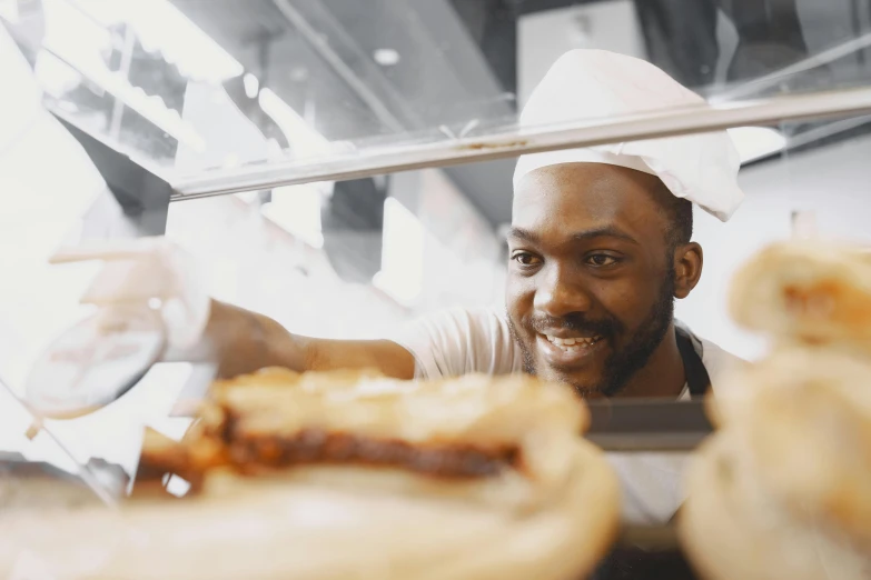 a man that is standing in front of some food, filling the frame, profile image, black man, close - up photograph