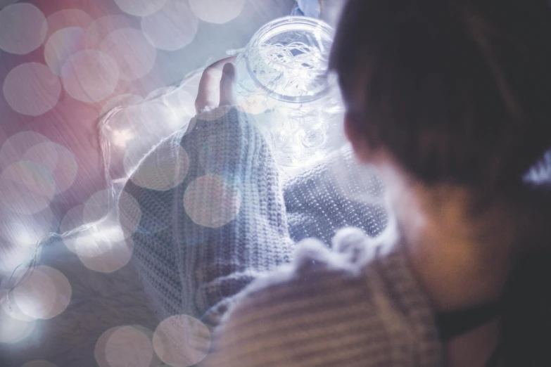 a close up of a person holding a cell phone, by Adam Marczyński, pexels contest winner, visual art, glowing jar, ethereal bubbles, cozy, pale light