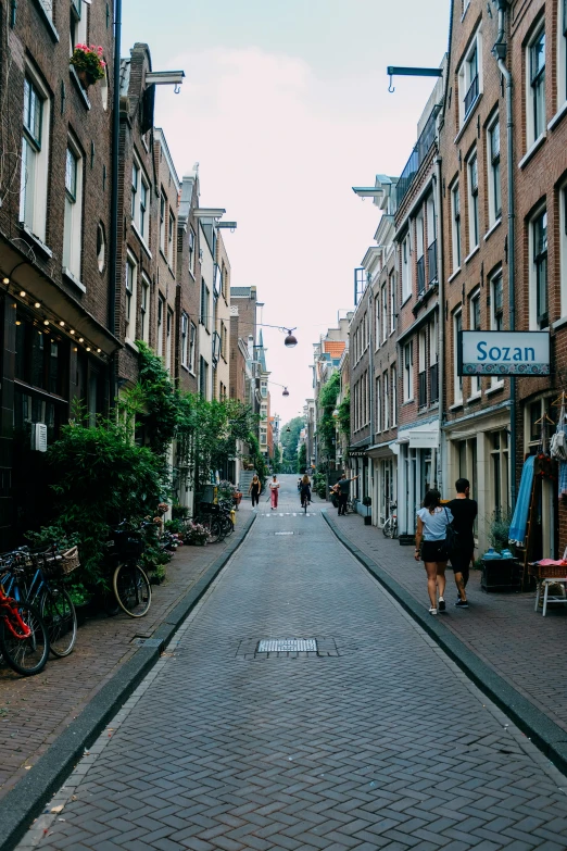 a couple of people walking down a street next to tall buildings, by Jacob Toorenvliet, view of houses in amsterdam, van, high quality upload, multiple stories