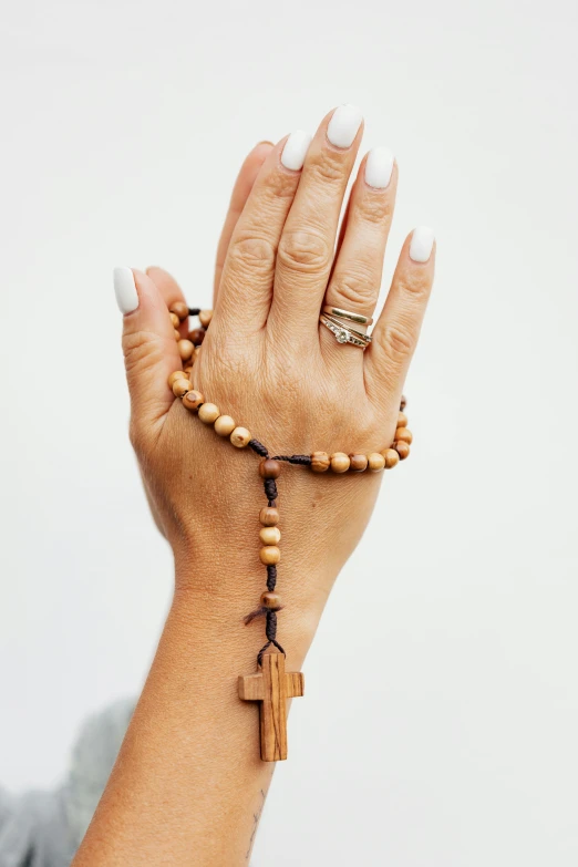 a woman holding a rosary in her hand, a digital rendering, pexels, wooden jewerly, single pair of hands, 2019 trending photo, made of wood