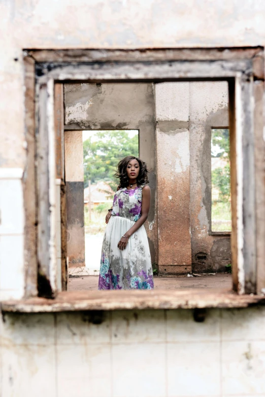 a woman that is standing in front of a window, an album cover, inspired by Gordon Parks, pexels contest winner, standing in ruins, wearing an african dress, standing in abandoned building, wearing a long flowery dress