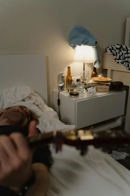 a man laying in bed playing a guitar, inspired by Nan Goldin, pexels contest winner, hyperrealism, booze, panoramic shot, scene from a dinner party, with an iv drip