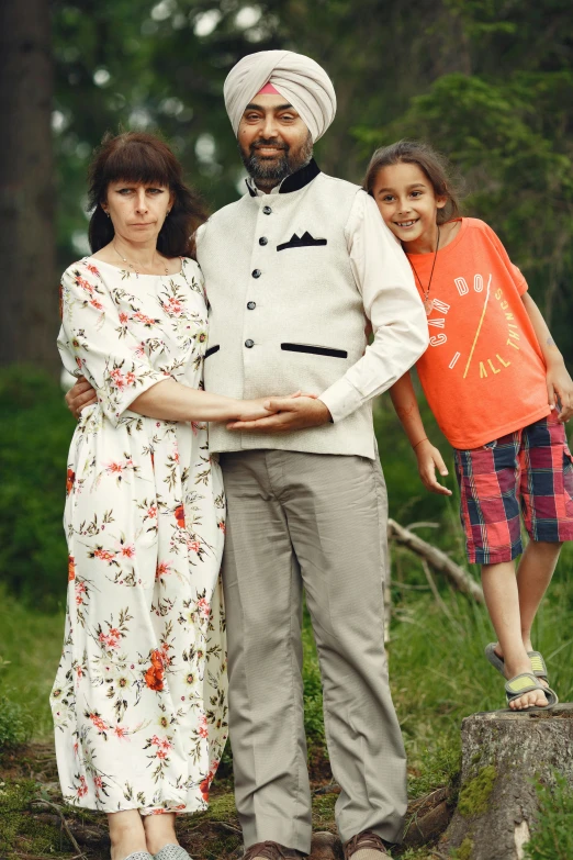 a man standing next to a woman and a child, pexels, international gothic, wearing a kurta, in front of a forest background, promotional image, cinematic outfit photo