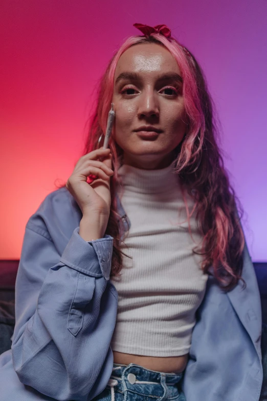 a woman sitting on a couch talking on a cell phone, an album cover, inspired by Elsa Bleda, trending on pexels, color field, portrait androgynous girl, glowing hair, looking the camera, color lights