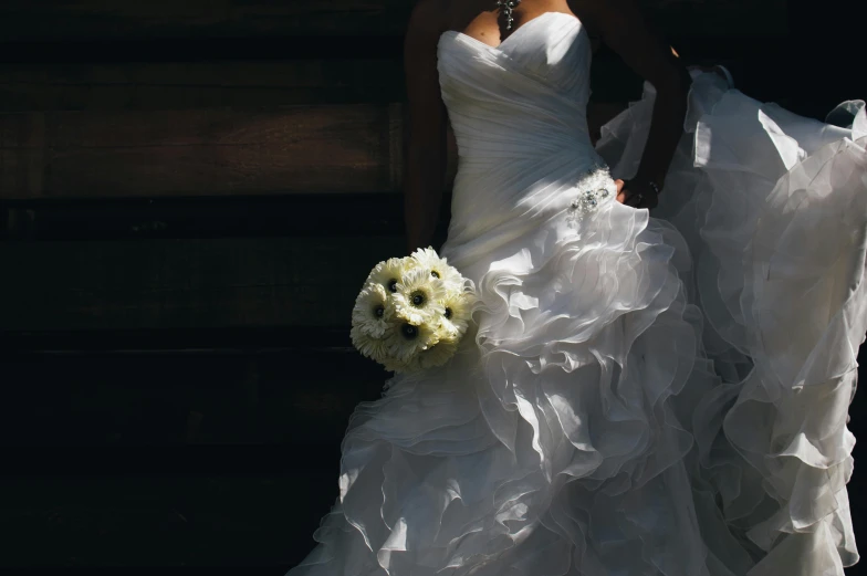 a woman in a wedding dress holding a bouquet, by Gwen Barnard, pexels contest winner, ruffles, front lit, stylised, formal attire