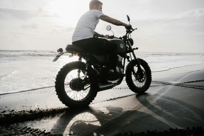 a man riding a motorcycle on top of a sandy beach, pexels contest winner, deus ex machina, avatar image, concrete, black