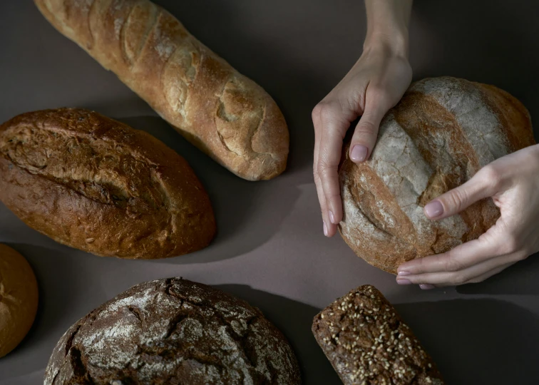 a table topped with lots of different types of bread, a portrait, inspired by Richmond Barthé, trending on unsplash, hyperrealism, hands reaching for her, high angle close up shot, high quality photo, “ iron bark