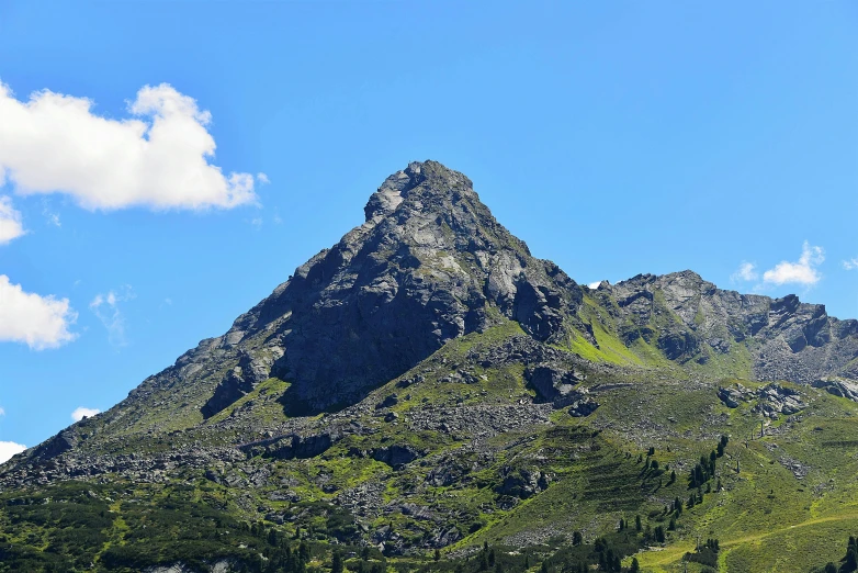 a group of cows standing on top of a lush green hillside, by Werner Andermatt, unsplash, les nabis, cone shaped, with snow on its peak, clear blue skies, rocky foreground