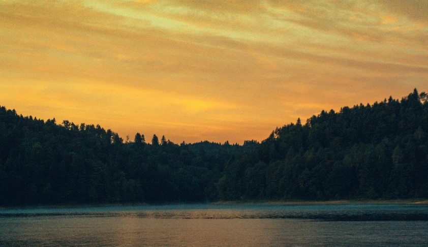 a large body of water with a forest in the background, a picture, inspired by Elsa Bleda, pexels contest winner, romanticism, orange skies, sunfaded, instagram post, late summer evening