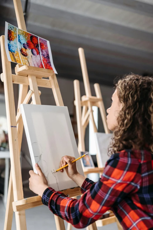 a woman is painting on an easel in an art studio, inspired by artist, pexels contest winner, academic art, kid drawing, symmetrical painting, award winning artwork, feat of artistic achievement