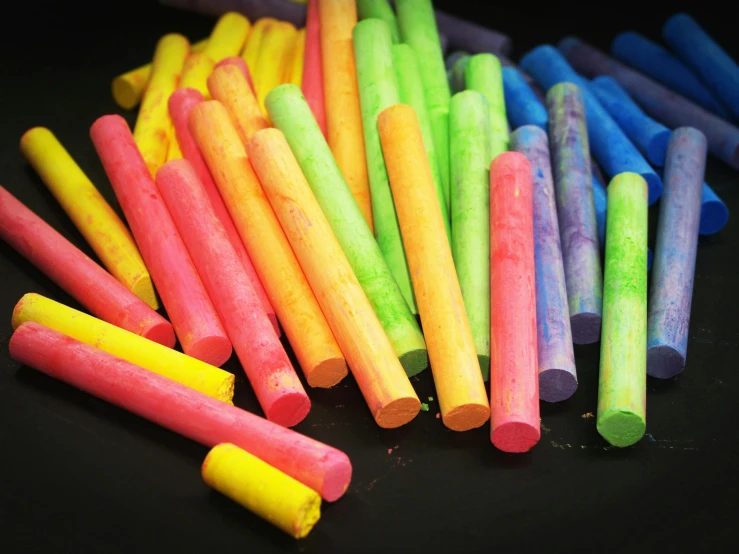 a pile of crayon sticks sitting on top of a table, chalk art, by Charlotte Harding, pexels, on a black background, clubs, chalked, thumbnail