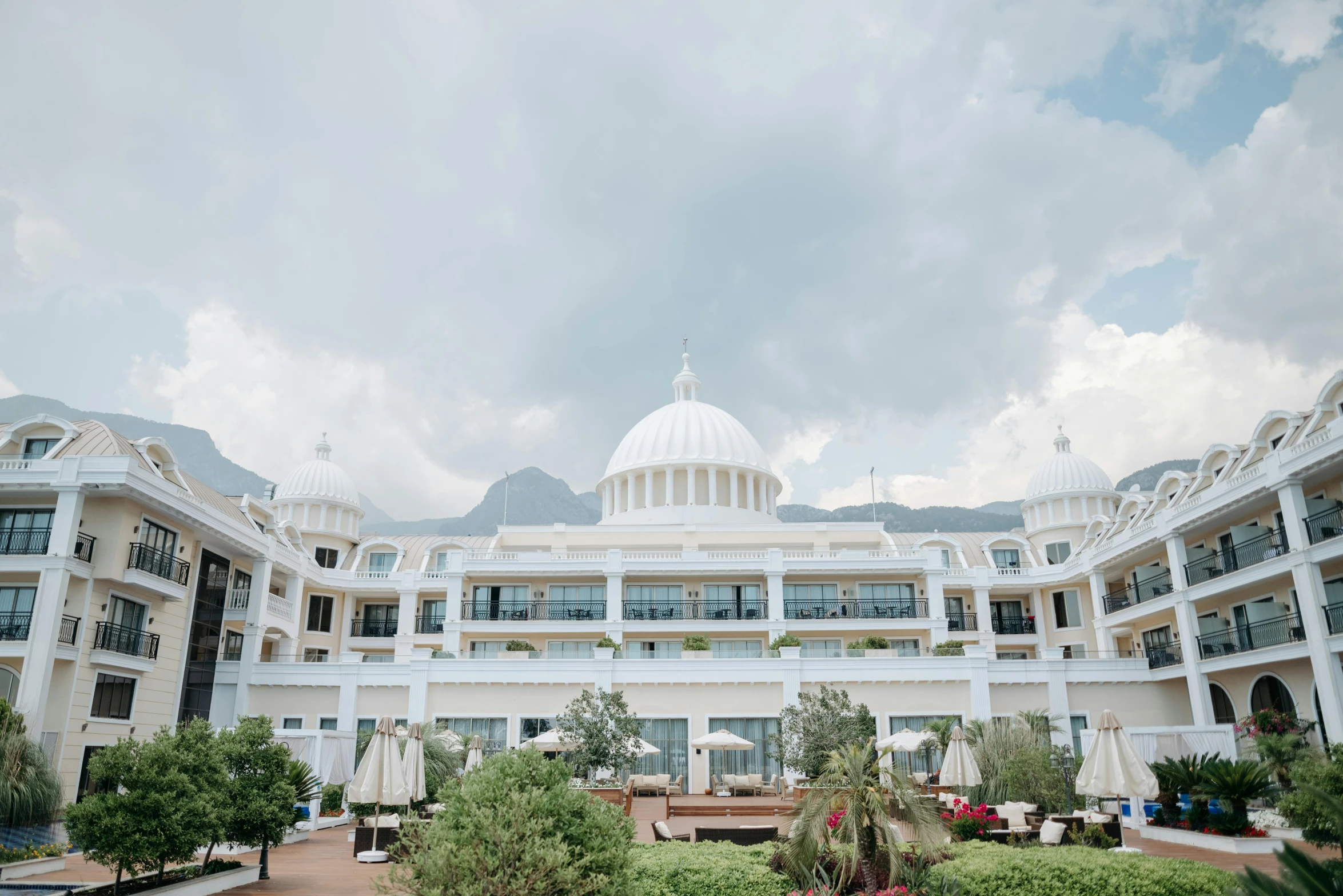 a large white building with a dome on top of it, unsplash contest winner, luxurious environment, parasols, mountain in the background, celestial gardens