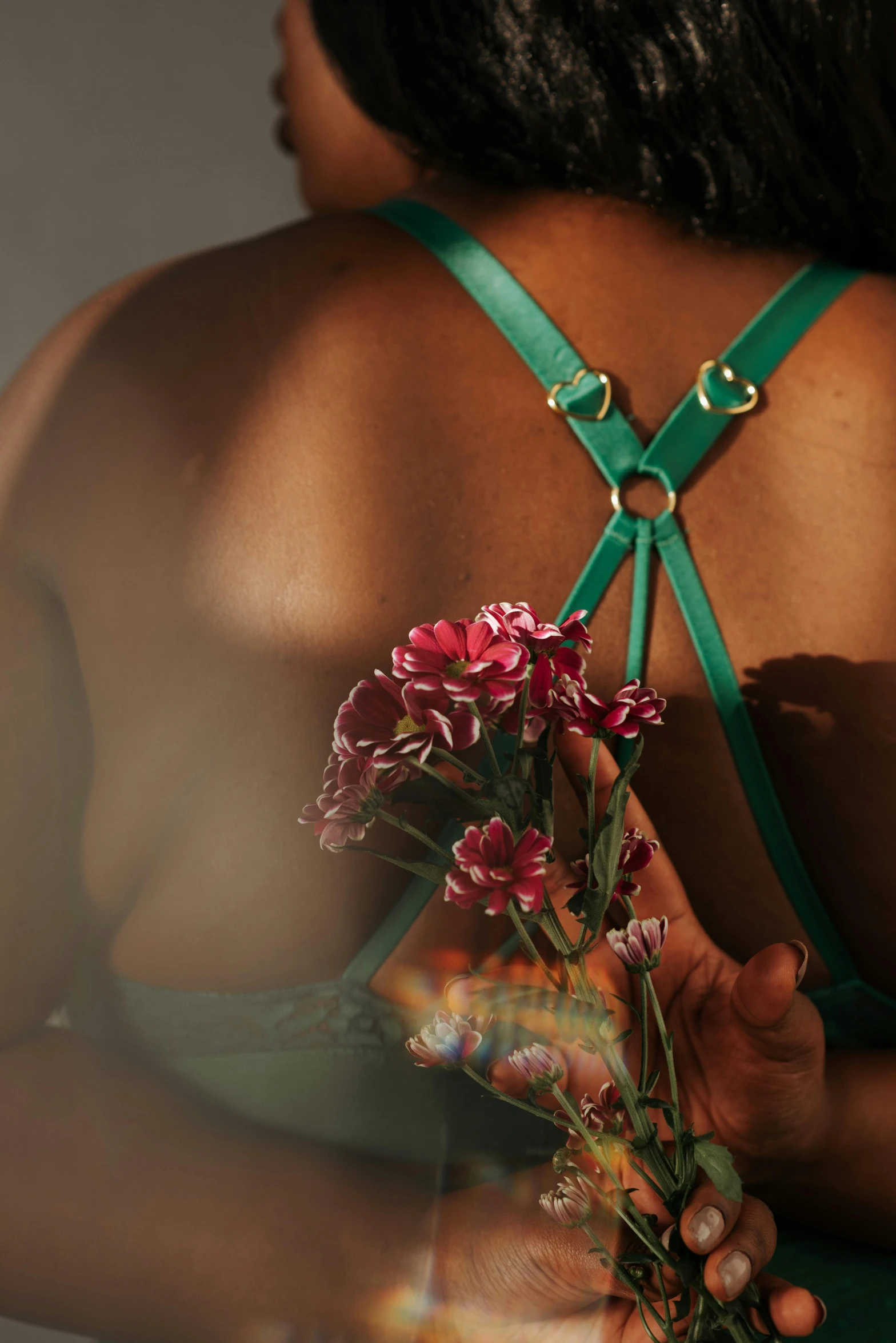 a woman in a green dress holding a bouquet of flowers, an album cover, inspired by Elsa Bleda, trending on pexels, renaissance, intricate leather suspenders, ( ( dark skin ) ), bralette, detail shot