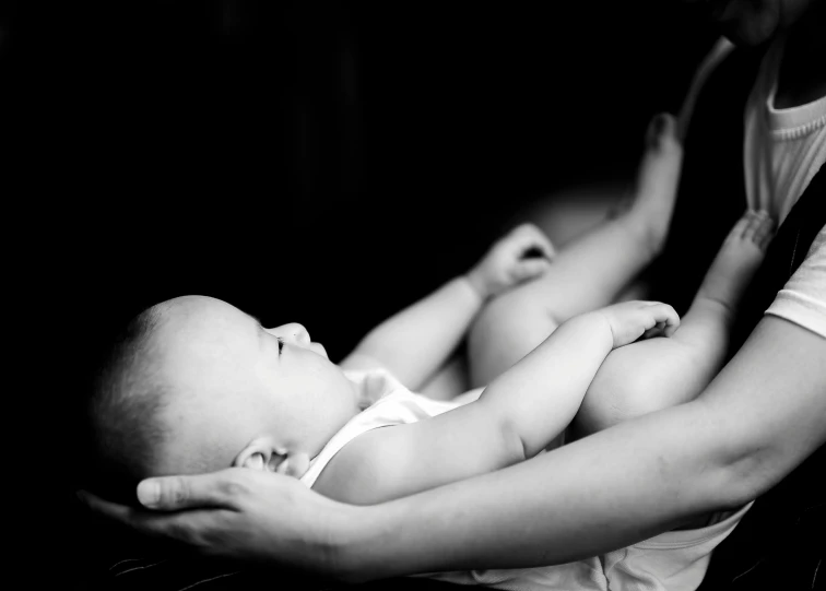 a woman holding a baby in her arms, a black and white photo, by Alice Mason, pexels contest winner, lying down, stretch, high contrast lighting, medium format. soft light