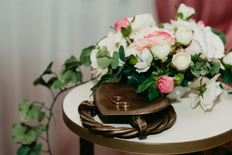 a bouquet of flowers sitting on top of a table, gold rings, on a pedestal